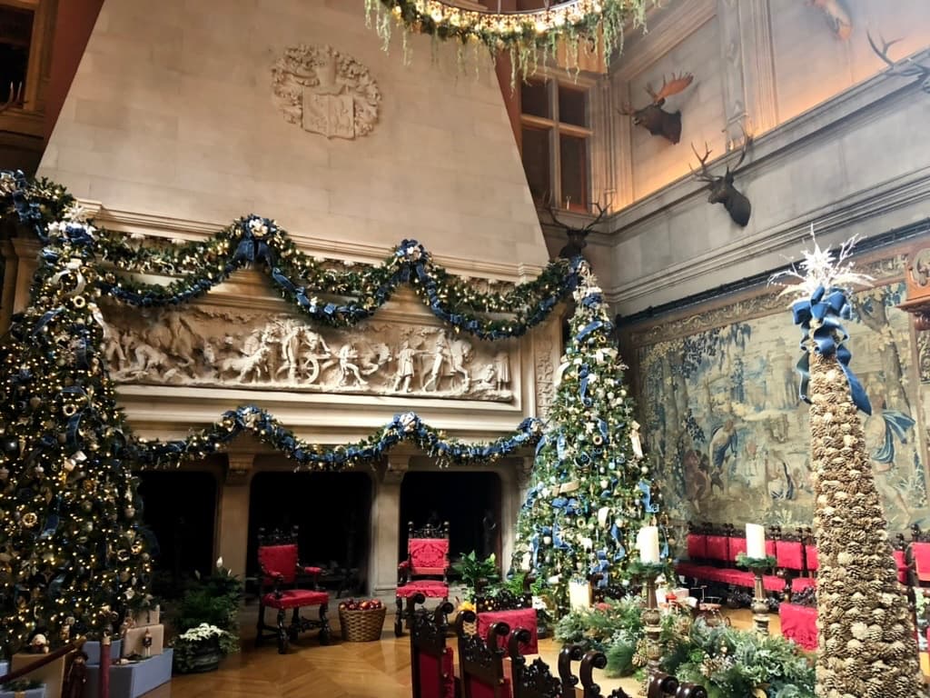 Towering decorated Christmas trees and tapestries in the Banquet Hall at Biltmore House