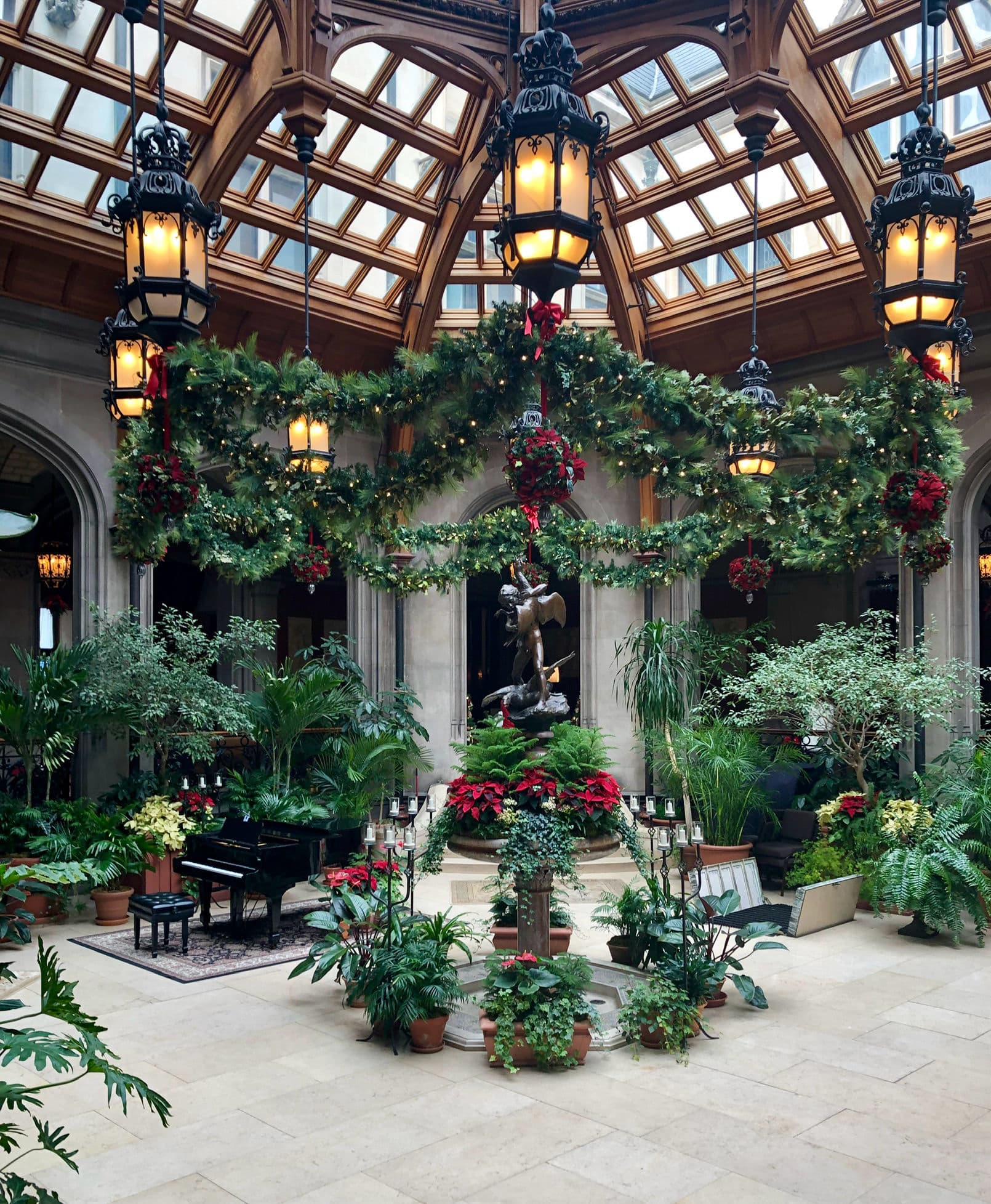The glass-roofed Winter Garden at Biltmore House decorated with garland and poinsettias