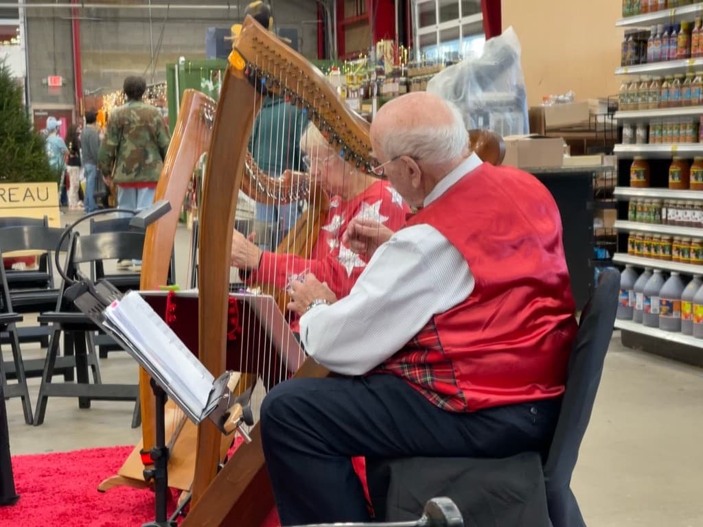 Harpists in red vests playing holiday music at the Western North Carolina Farmers Market