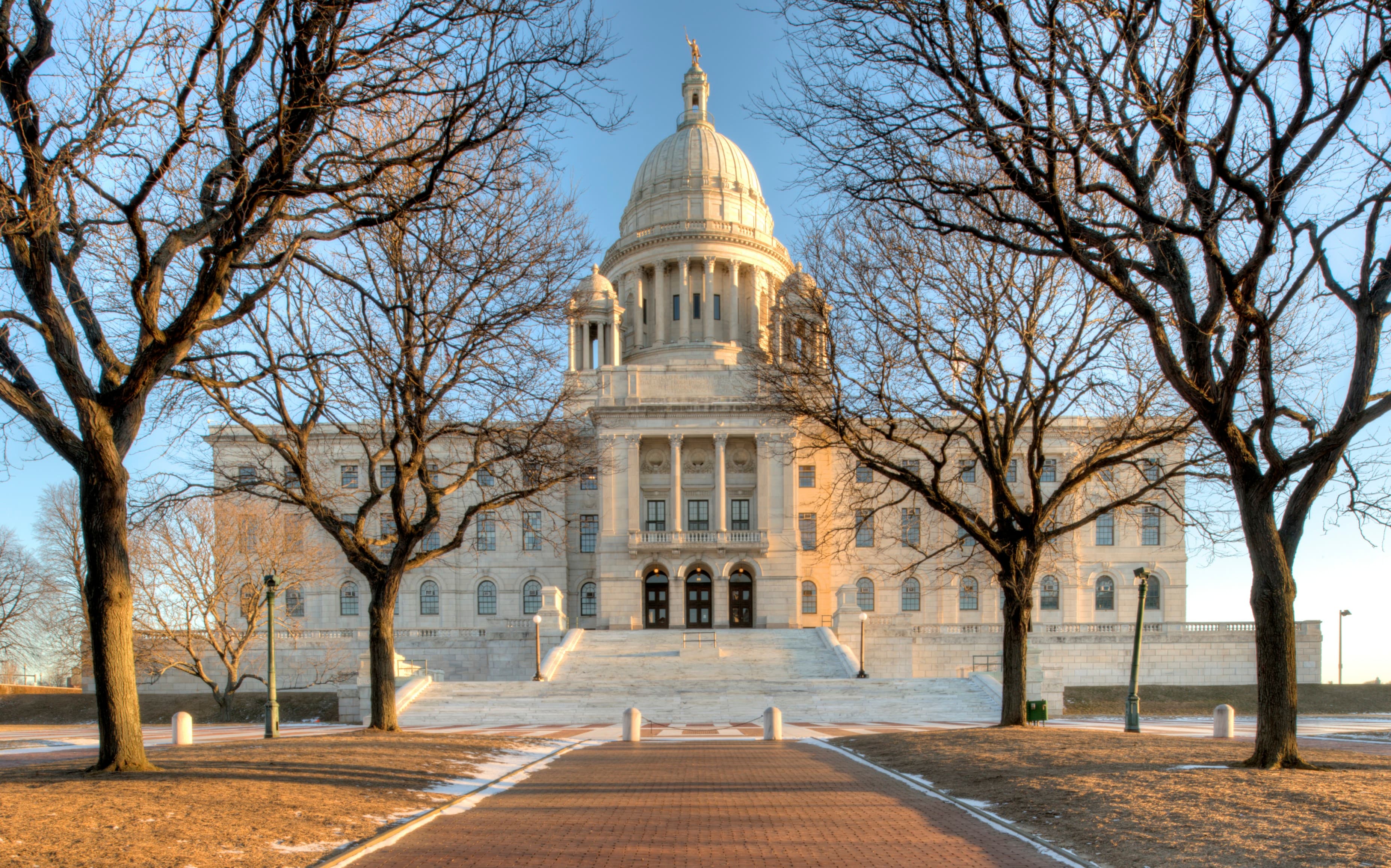 The Rhode Island State House in Providence framed by trees in warm light