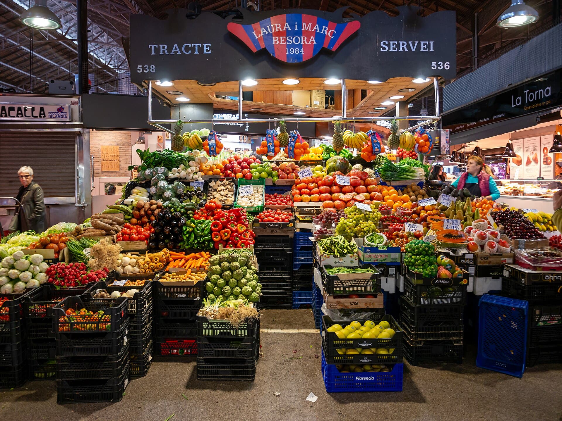 A produce stall filled with fruit and vegetables inside La Boqueria market